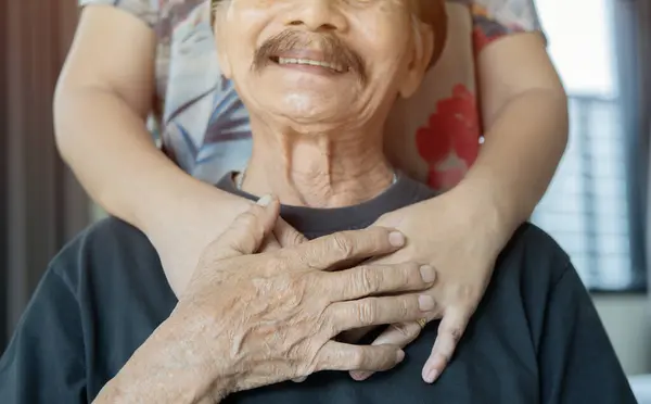 Shot of smiling older father hugging hands of grownup daughter from back. Selective focus. Grandparent concept.