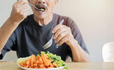 Sebzeler vitamindir. Yaşlı adam sebze yiyor. Kapatın. Ellere odaklan. Sağlıklı yaşam tarzı kavramı