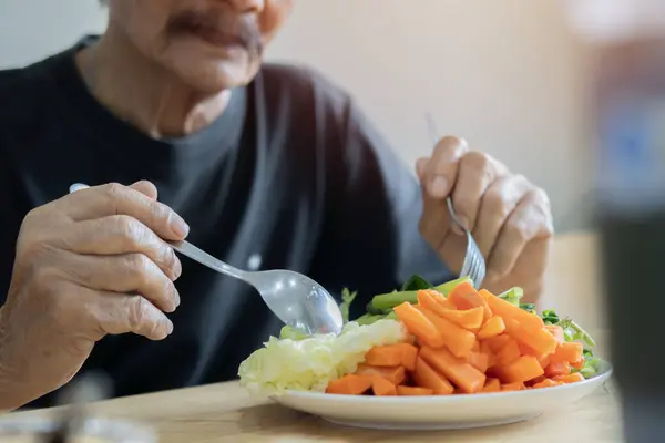 Cropped view of an older man with green healthy food on the table indoors at home. Concept of healthy nutrition in older age