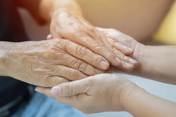 Hands of young adults and older man, Asian caregiver holding Asian senior man's hands, no face