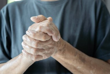 Yaşlı adamın durduğu ve nazikçe göğsüne yakın el ele tutuştuğu görüntüler. Seçici odaklanma konseptine nasıl yardımcı olabilirim?.