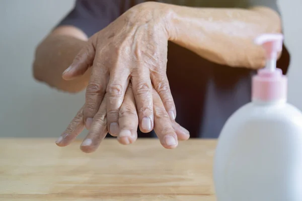 Cold season hands skin protection. Closeup old man applying protective cream on hands. Selective focus on hands.