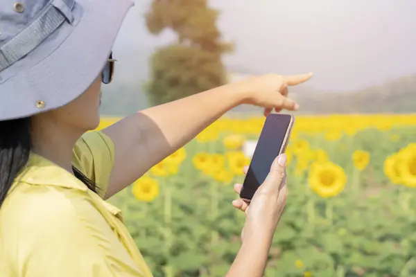 Woman farmer making video inspection of agricultural field with sunflower plants. Smart farming, farm, agriculture