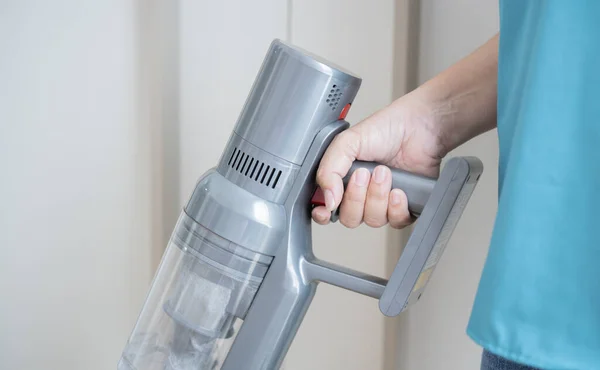 Cropped image of maid hand using handheld cordless vacuum cleaner to vacuuming and cleaning home.