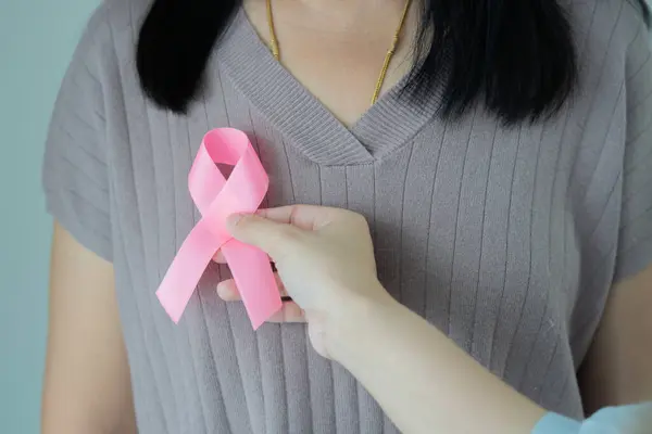 Doktor eli pembe kurdele kanseri olan bir kadına destek oluyor. Sağlık ve tıbbı kavramsallaştır