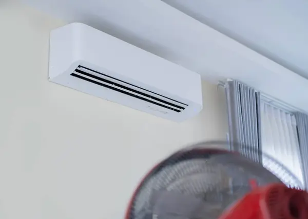 Air conditioner on wall background and electric fans placed at front in living room. Selective focus.