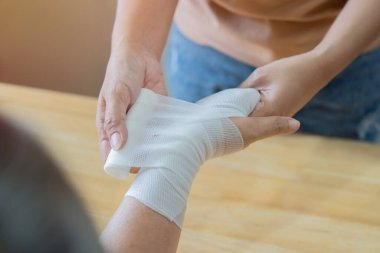 Kızı, annesinin bileğini ve kolunu yaralı elleriyle sarmalamış. İlk yardım, kaza ve yaralanma tedavi kavramı.