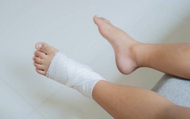 Düştükten sonra meydana gelen küçük bir kaza yüzünden bir çocuğun sargılı ayaklarının üst görüntüsü. Yaralanma / travmadan sonra çocuklara ilk yardım