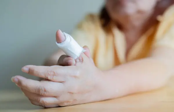 Yaşlı kadın sargı bezi ile yaralı bir parmak. Seçici odaklanma, kapat. Tıbbi konsept