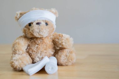 Oyuncak ayının kafasında gazlı bez var. Taklit alanı olan tahta masada oturuyor. Çocuk Yaralama Konsepti