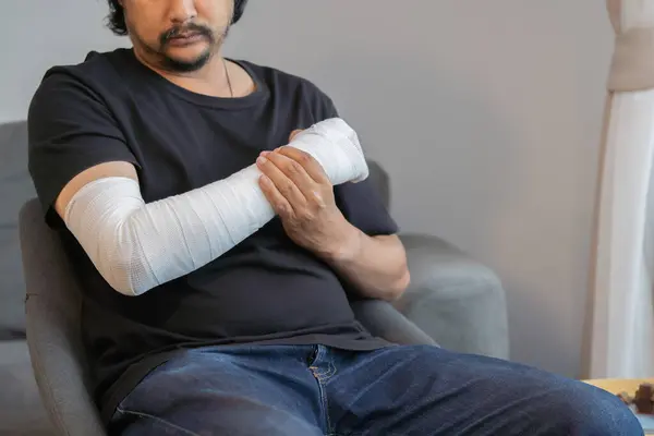 Kolu ve eli bandajlı bir adam evde. İlk yardım, kaza sonrası tedavi. Boşluğu kopyala