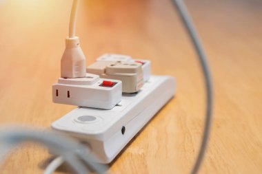 Tahta masadaki maltiple elektrik prizine bağlı bir elektrik prizi. Elektrik tüketimi kavramı. Seçici odak.