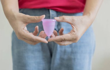Silikon adet bardağı. Bir kadın elinde regl bardağını tutuyor. Kadın sağlığı ve alternatif hijyen. Sıfır atık alternatif
