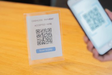 El ele tutuşup QR kodunu tarıyoruz. Adamın biri QR kodu ile ödeme yapıyor. Konuya seçici odaklanma.