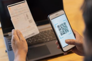 Uygulama üzerinden QR kodunu taramak için cep telefonu tutan bir erkek. Evden internet üzerinden ödeme. 