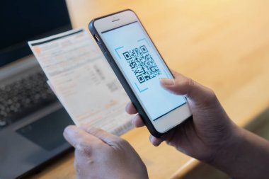 Erkek eller uygulama üzerinden QR kodunu taramak için cep telefonu kullanıyor. Evden internet üzerinden ödeme yapmak çok uygun. Kendine dikkat et ve sosyal mesafeni koru.