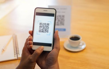 Kahve dükkanında etiketi tarayan adam. QR kodu ödemesi, E cüzdanı, nakitsiz teknoloji konsepti. Seçici odak.