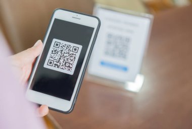 QR kodu ile ödeme yapan bir kadın. Müşteri el yapımı ödemeyi akıllı telefon ve tarama koduyla kapat.