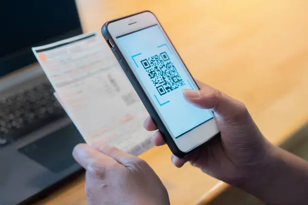 Erkek eller uygulama üzerinden QR kodunu taramak için cep telefonu kullanıyor. Evden internet üzerinden ödeme yapmak çok uygun. Kendine dikkat et ve sosyal mesafeni koru.