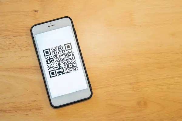Barkod okuyucu, QR kod ödemesi, nakitsiz teknoloji, dijital para konsepti. Taklit alanı olan ahşap arkaplan üzerinde mobil ekranda QR Kodu.