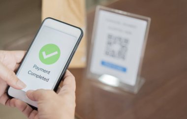 Kapalı eller, mobil uygulamadan elektronik işlem yoluyla para aktarmak için akıllı telefonu tutuyor. Seçici odak.