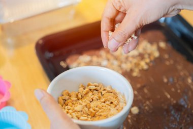 Kadın el fırıncısı. Masada fındıklı lezzetli pasta ile dekore ediyor. Ev yapımı tatlı konsept. Yan görünüm, seçici odak.