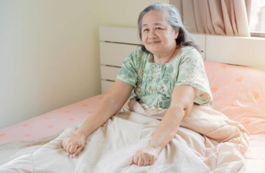 Sağlıklı uykudan uyanan olgun, mutlu bir kadın rahat bir yatakta uyanıyor. İyi uykular..