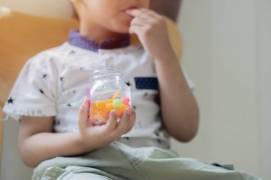 Küçük bir çocuğun el ele tutuşup bir kavanozda şeker olan jöle topunu tutuşu. Atıştırma zamanı. Seçici odak.