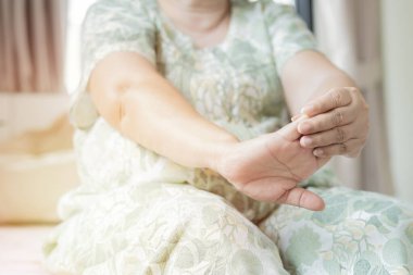 Fizyoterapi sırasında yaşlı bir kadın sabahları ellerini yatak odasına koyuyor. Yaralı dirsek ve el bileği için rehabilitasyon tedavisi.