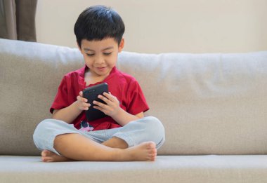 Asyalı şirin çocuğun portre resmi ve akıllı telefon uygulamasını online tarama ya da evde video izlemek için kullanın. Boşluğu kopyala.