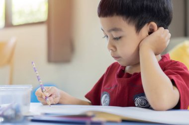 Çocuklar okula geri döner. Çocuklar çalışır ve anaokulu için öğrenirler. İlköğretim sınıfının küçük çocuğu resim yapıyor. Seçici odak.
