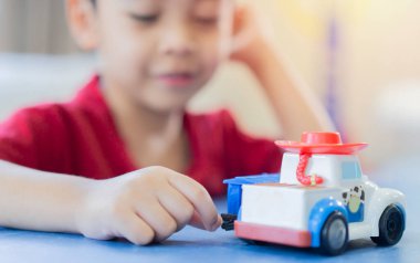 Küçük tatlı Asyalı çocuk, anaokulu çocuğu, kamyonla oynayan çocuk, evde araba oyuncağı. Seçici odak.