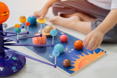 Çocuklar astronotçuluk oynuyor. Güneş sistemi oyuncağı ve gezegen dekorasyonu olan küçük bir çocuk. Yaratıcı çocuk, geleceğin mesleği.