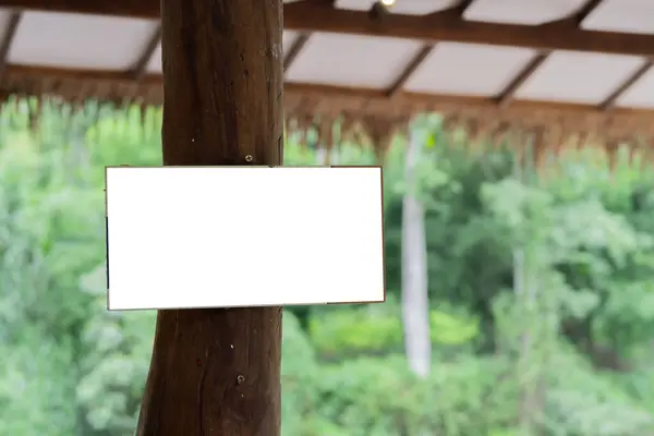 stock image Blank wooden board sign installed on a large wooden pole under roof. Tropical cafe or hotel sign mockup