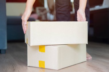 Teslimat paketini elinde tutan bir kadın, kapıda duran karton kutular. Paket dağıtım hizmeti kavramı.