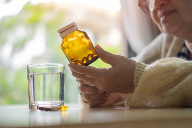 Son sınıf öğrencisi bir kadının elinde bir şişe ilaç tutarken ve dikkatlice bakarken görüntüsü. Seçici odaklanma. Yaşlılık konsepti için ilaç.