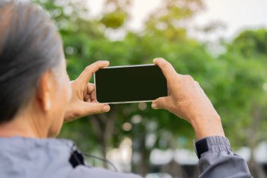 Son sınıf öğrencisinin cep telefonuyla fotoğraf çekerken ya da arka planda akıllı telefonlu selfie çekerken. Uzayı kopyala Yaşlılar yaşam tarzı kavramının sosyal medyası.