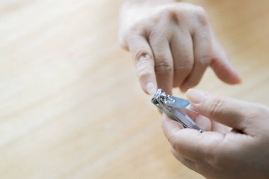 Tırnak makasıyla insan eli, kişisel hijyen, tahta masada kesilmiş tırnaklar. Uzayı kopyala Tırnak kesme kavramı.