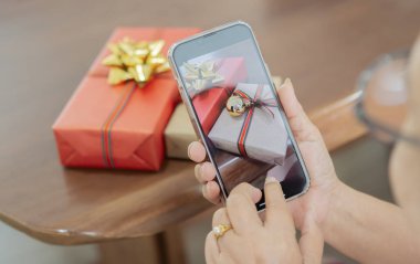 Mutlu büyük ebeveynler ailelerinden cep telefonuyla bir fotoğraf Noel hediyesi alıyor. Evdeki akıllı telefondan sanal parti görüntülü görüşme. Omzunun üstünden