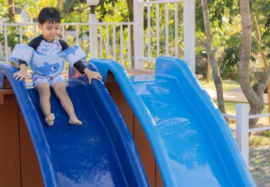 Yüzme havuzunda yüzen mutlu bir çocuk yaz tatilinde güzel bir su parkında eğleniyor..