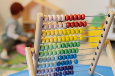 Küçük çocuk halıda renkli oyuncaklarla oynuyor. Anaokulunun çocuk parkında bir blok tutuyor, gülümsüyor. Numaralandırma oyuncağına odaklan.