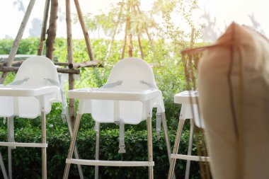 Beyaz bebek sandalyeleri bir bahçe atmosferi restoranında hizmet için hazırlandı. Seçici odak.