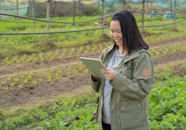 Serada dijital tabletle gülümseyen bahçe işçisinin yan görünüş portresi. Sapı kopyala.