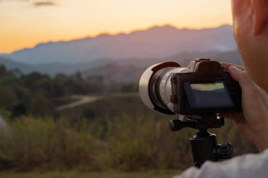 DSR kamerasıyla dağda fotoğraf çeken bir adamın arka plan görüntüsü. Seyahat, tatiller, profesyonel serbest çalışma ve aktif yaşam tarzı konsepti