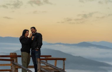 Yüksek bir dağın görüş açısında duran bir çift kameranın ekranında fotoğraflarına bakıyor.