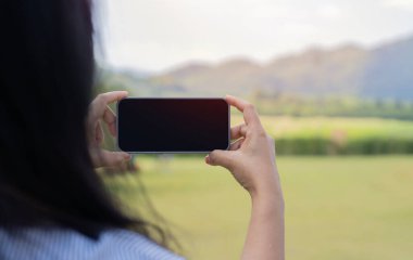 Arka planda elinde telefon olan bir kadının manzarası var. Mobil iletişimin ve internetin erişilebilirliği