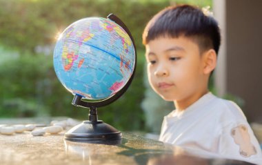 Mutlu Asyalı çocuk dışarıda oynarken Globe küresel eğitim dünyası haritasına bakıyor ve eğleniyor. Çocuk eğitimi konsepti. Seçici odak.