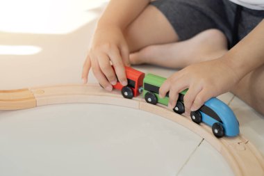 Çocuklar oyuncak tren konseptini seviyorlar. Yeni yürümeye başlayan çocuk ahşap trenlerle meşgul. Demiryolu ve bloklar inşa ediliyor.