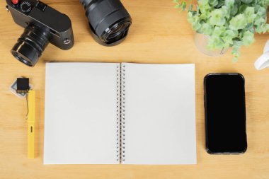 Kameralı, hafıza kartlı, objektifli ve ahşap masa arkaplanlı düz bir kağıt defter. Boşluğu kopyala.