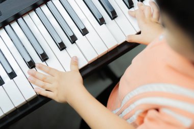 Küçük bir öğrencinin ellerini kapamak piyano çalmak, öğrenmek ve pratik yapmaktır. Çocuklar için müzik yeteneği. Çocuklar için hobi ve aktivite. Seçici odak.